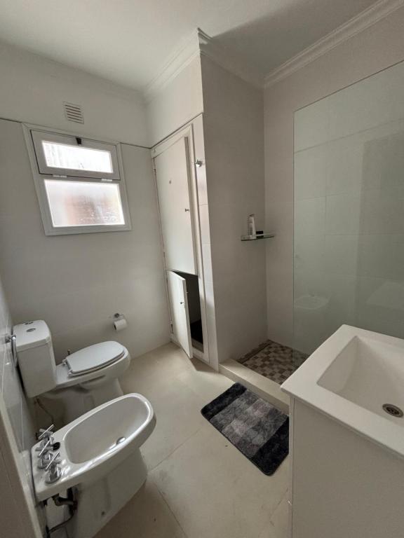 a bathroom with a white toilet and a sink at Casa Moras in Necochea