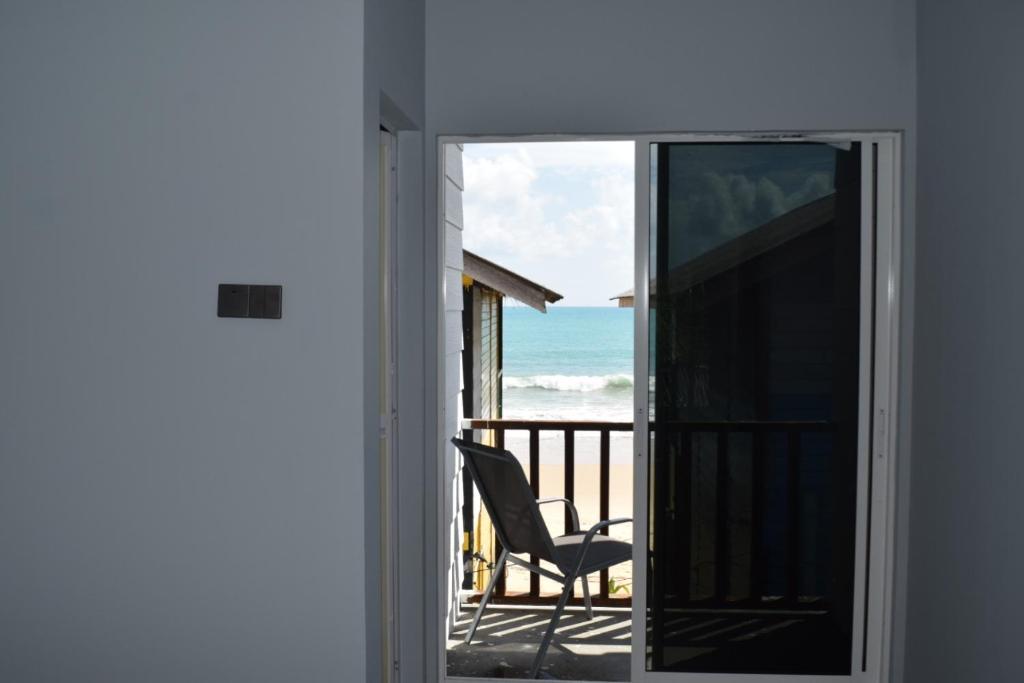 a chair on a balcony with a view of the ocean at Beach Shack Loft Side Seaview in Tioman Island