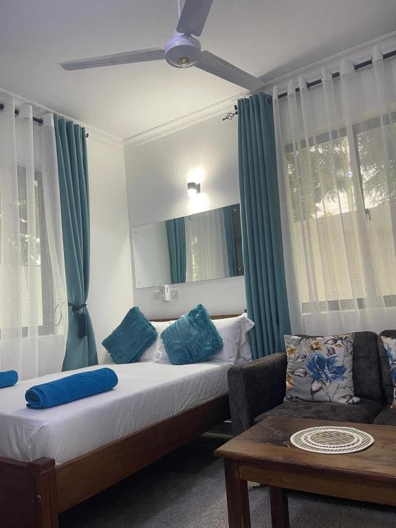 a bedroom with a bed with blue pillows and a couch at Mombasa Apartments in Mombasa