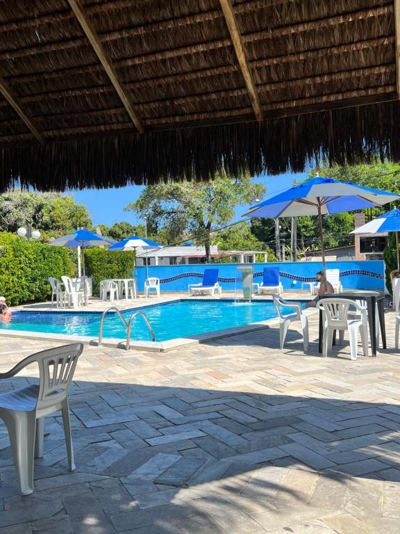 ナタールにあるYacht villageのスイミングプール(テーブル、椅子、パラソル付)