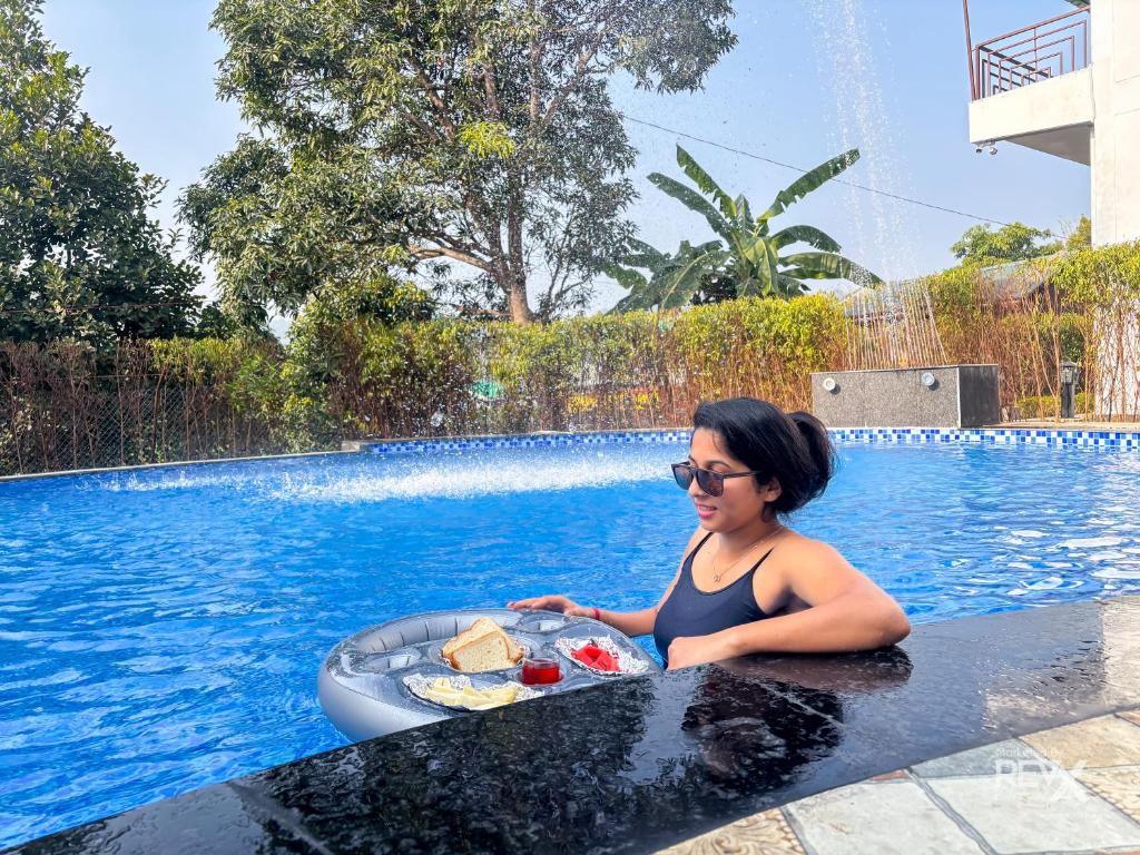 una donna in piscina con un vassoio di cibo di Wonderwood Corbett Resort -1min walk to River with Deep Jungle Trail a Ramnagar