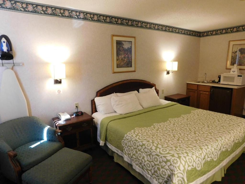 a hotel room with a bed and a chair at Days Inn by Wyndham Lexington NE in Lexington