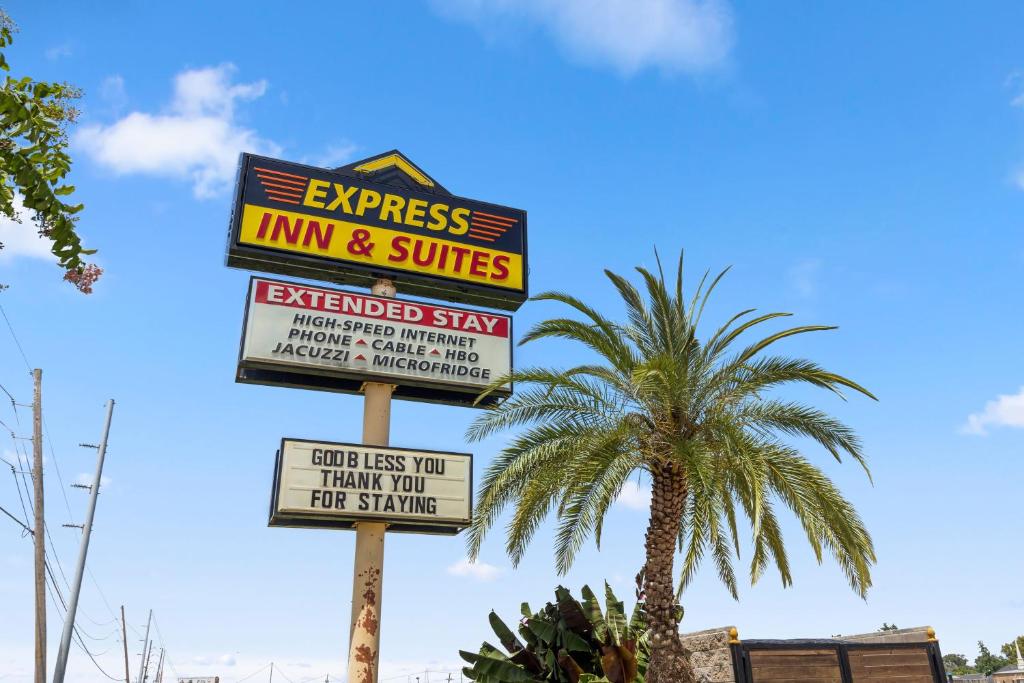 a sign for a inn and suites next to a palm tree at Express Inn & Suites Westwego in Westwego
