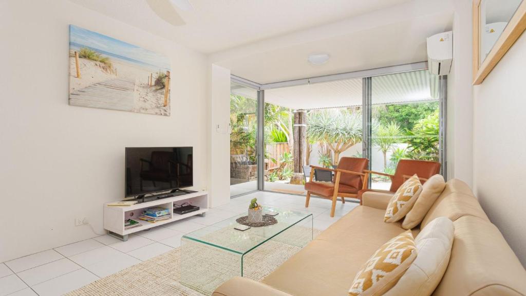 a living room with a couch and a television at Sawtell Beachside on 4th in Sawtell