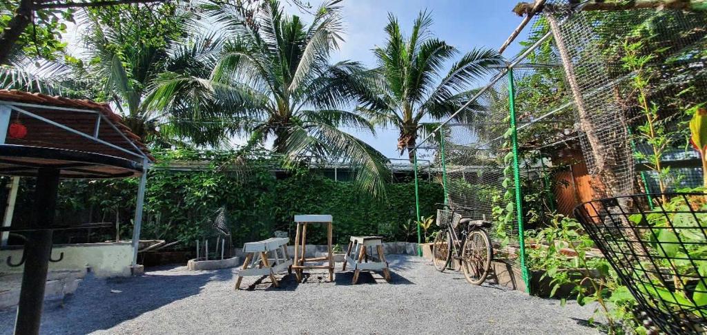 a patio with chairs and a fence with palm trees at Happy Farm Homestay in Ấp Long Ðại
