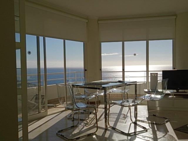 a dining table and chairs in a room with windows at The Sunrise of your Dreams with Total Ocean View in Funchal