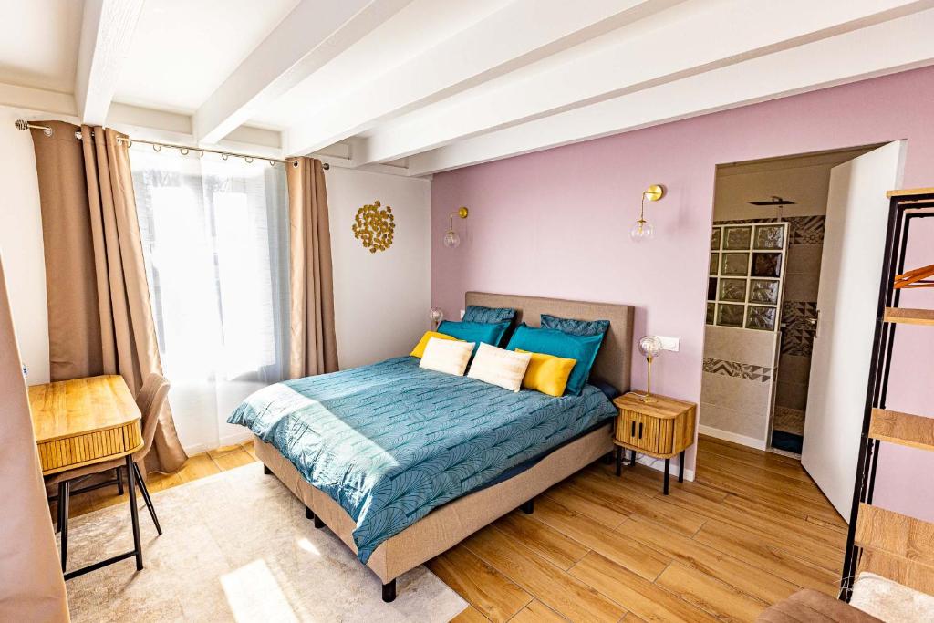 une chambre avec un lit avec des oreillers bleus et jaunes dans l'établissement La Plordonnière, à Mornac-sur-Seudre