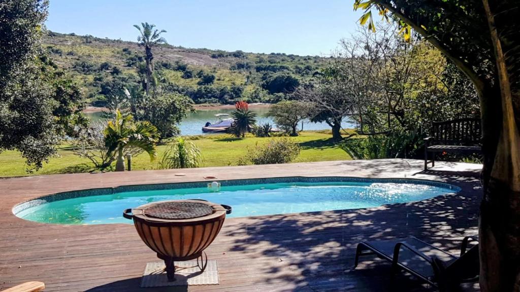 a swimming pool on a deck with a view of a river at Coelacanth Sea & River Lodge in Kayserʼs Beach