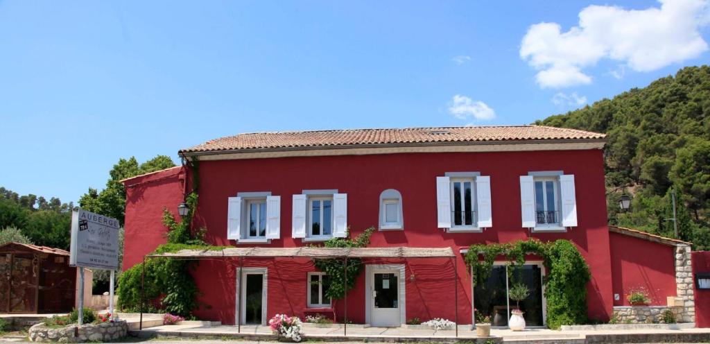a red building in front of a mountain at Auberge les Galets in Peyruis