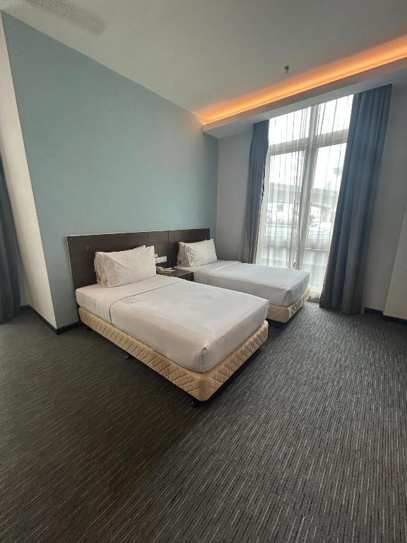 2 Betten in einem Hotelzimmer mit Fenstern in der Unterkunft Scott Hotel KL Sentral in Kuala Lumpur