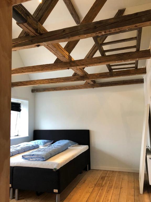 a bedroom with a bed in a room with wooden floors at Stor villa med privat have in Bredebro
