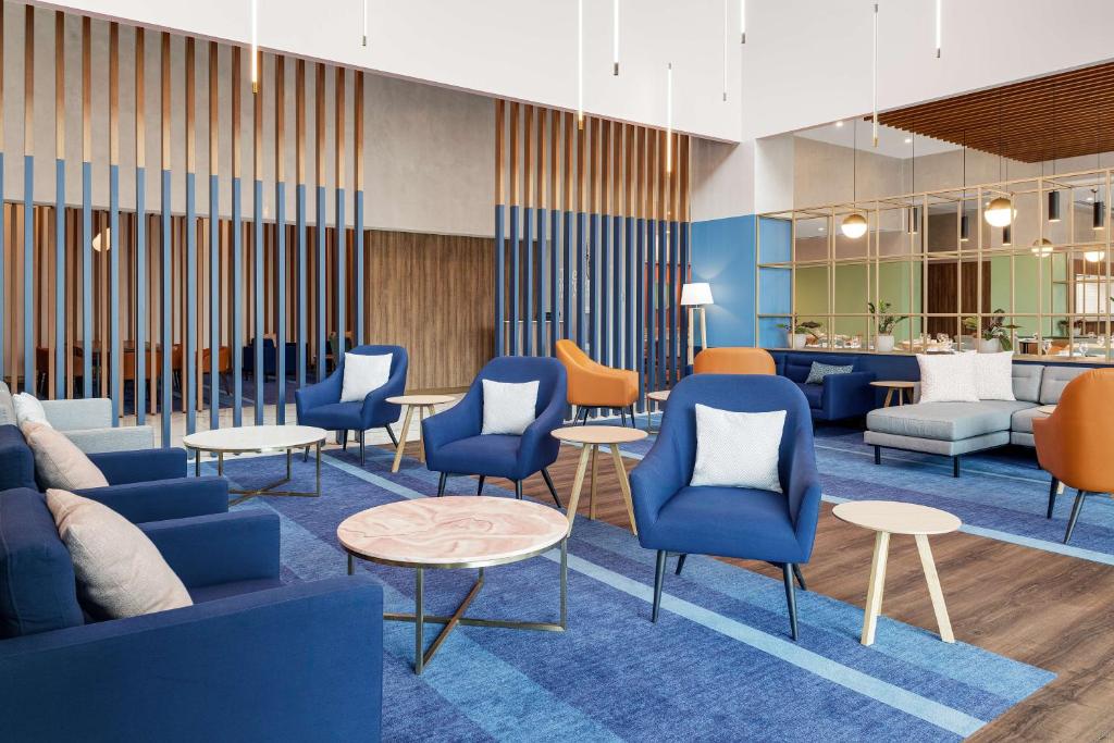 a waiting room with blue chairs and tables at Hilton Garden Inn San Jose Airport City Mall in Alajuela City