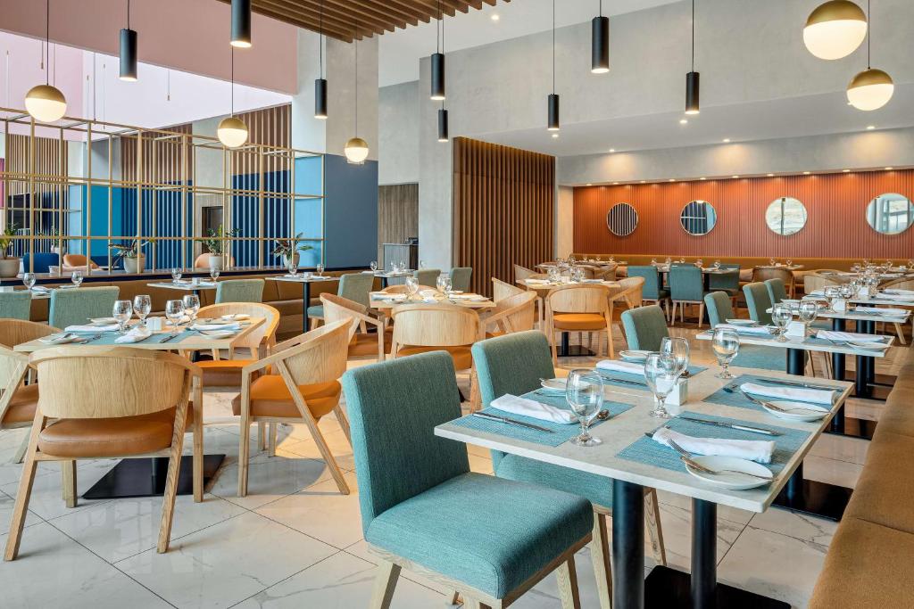 a dining room with tables and chairs and a restaurant at Hilton Garden Inn San Jose Airport City Mall in Alajuela City