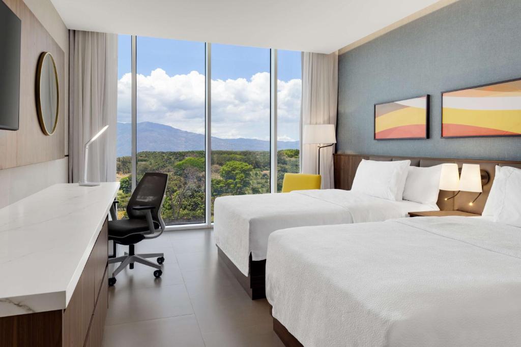 a hotel room with two beds and a desk at Hilton Garden Inn San Jose Airport City Mall in Alajuela City