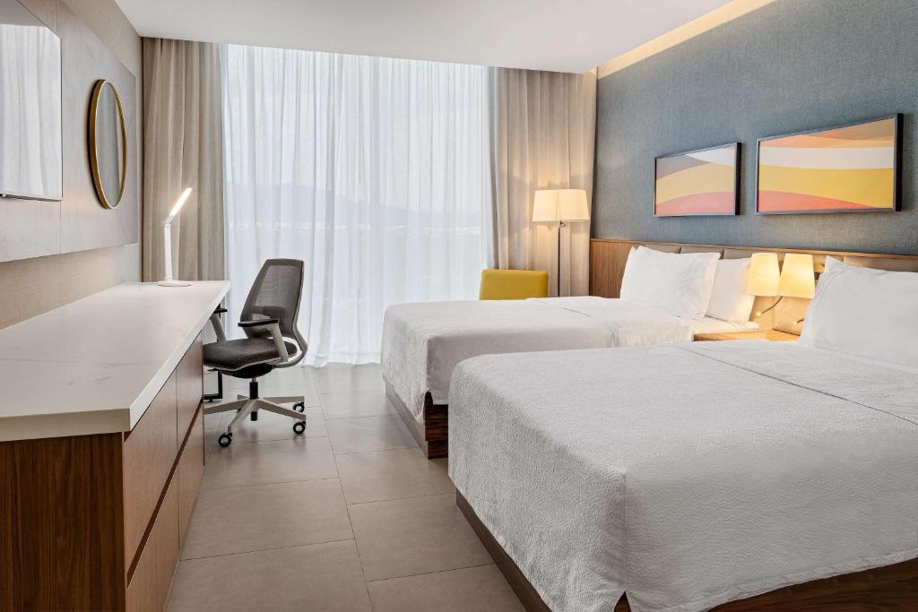 a hotel room with two beds and a desk at Hilton Garden Inn San Jose Airport City Mall in Alajuela City