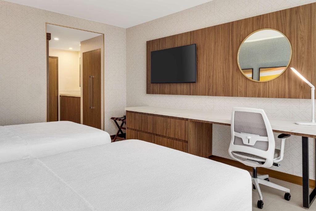 a hotel room with two beds and a desk and a mirror at Hilton Garden Inn San Jose Airport City Mall in Alajuela City