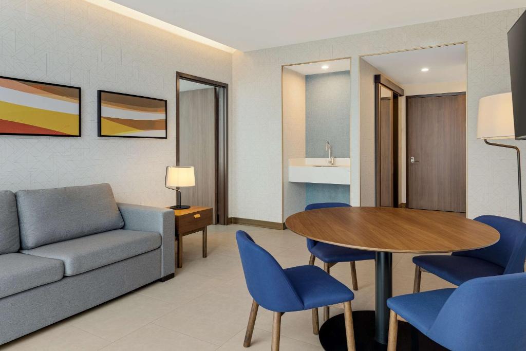 a living room with a couch and a table and chairs at Hilton Garden Inn San Jose Airport City Mall in Alajuela City