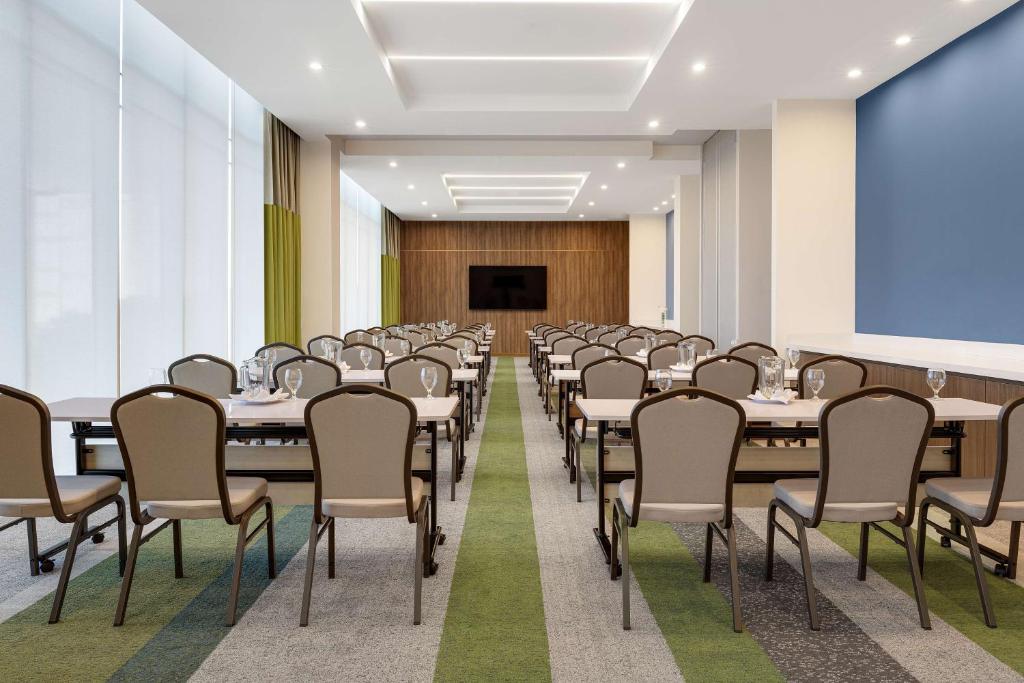 a conference room with tables and chairs and a projection screen at Hilton Garden Inn San Jose Airport City Mall in Alajuela City