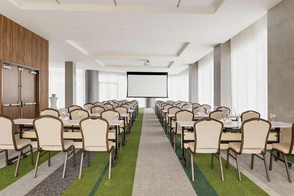 a conference room with tables and chairs and a projector screen at Hilton Garden Inn San Jose Airport City Mall in Alajuela City