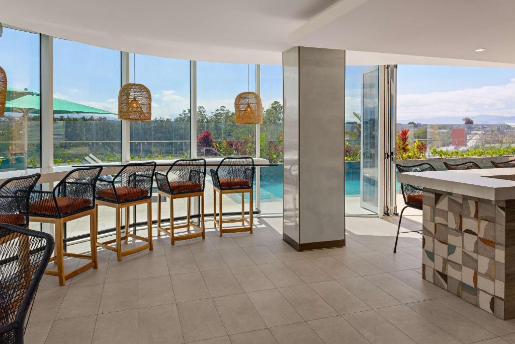 a restaurant with a bar with chairs and a pool at Hilton Garden Inn San Jose Airport City Mall in Alajuela City