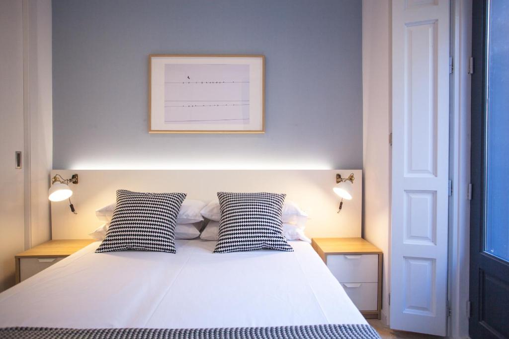 1 dormitorio con 1 cama con 2 almohadas blancas y negras en Apartment in Malasaña, en Madrid