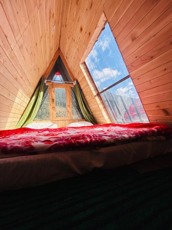 a bed in a room with a large window at Skytouch cottage stargazing in Jibhi