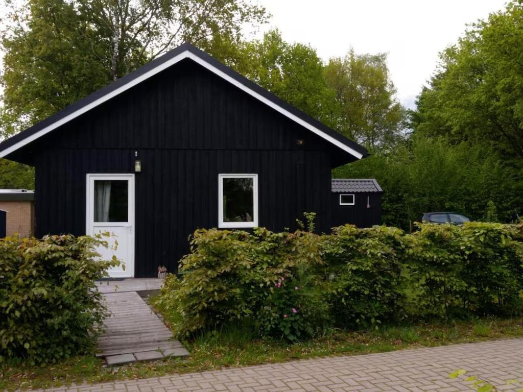 una casa negra con una puerta blanca en Bungalow Lijsterbes | 4 personen - Vakantiepark De Kremmer, en Gasselte