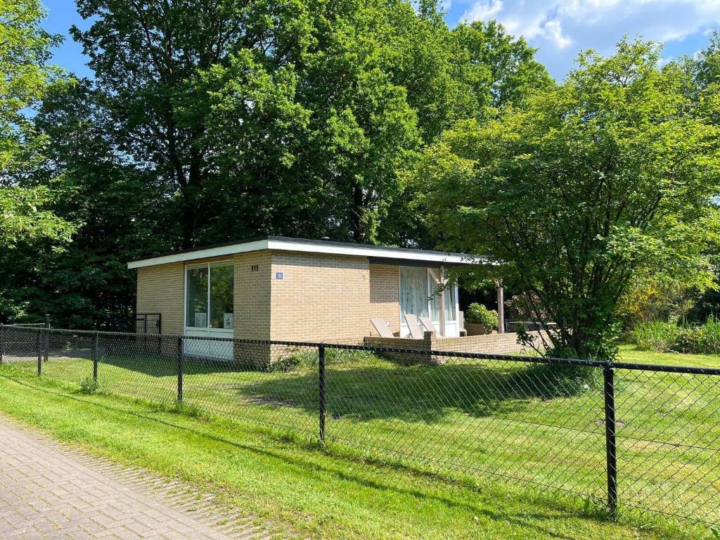 a small house behind a fence in a field at Bungalow Zandzegge | 4 personen - Vakantiepark De Kremmer in Gasselte