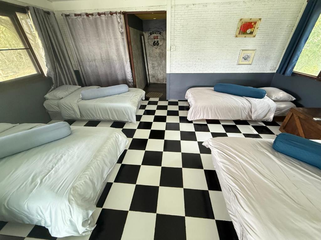 a room with four beds and a checkered floor at บ้านเชิงเขา โฮมสเตย์ in Ban Mai