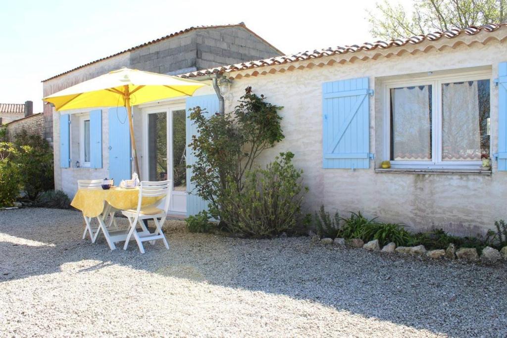 - une table et des chaises avec un parasol en face d'une maison dans l'établissement Maison 2 pièces 2 couchages Dolus d'Oléron DDO000-022, à Dolus-d'Oléron