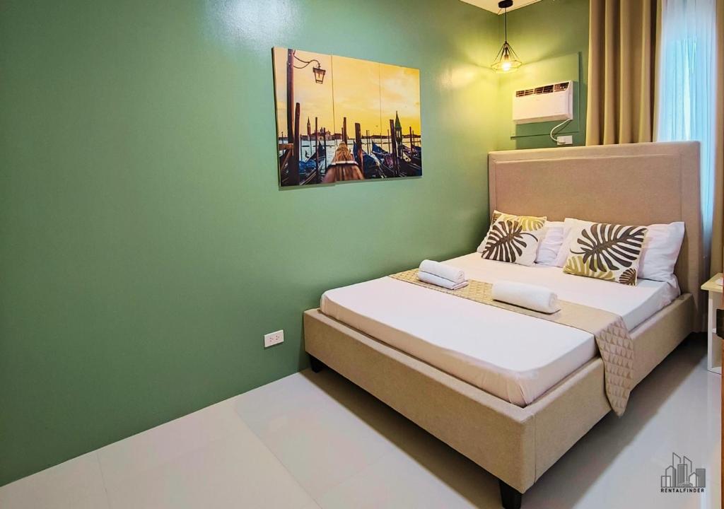 a bedroom with a bed with a green wall at Puerto Princesa Luxury 1BR Rental Homes with FREE Gym, Pool & Parking - B1 5Pearl in Puerto Princesa City