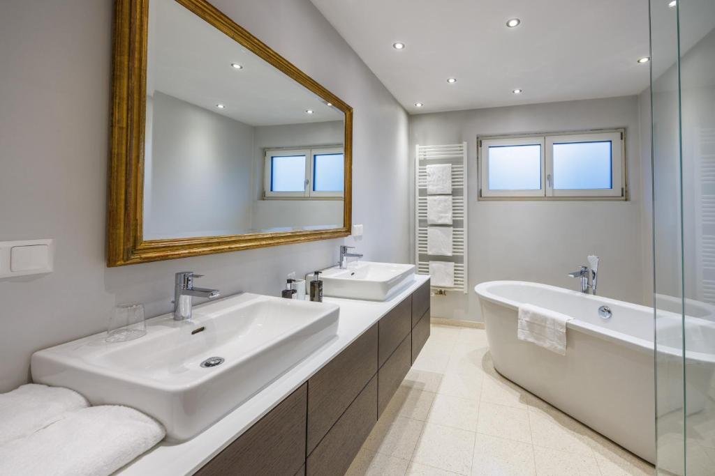 bagno con 2 lavandini, vasca e specchio di Hotel Dermuth Klagenfurt a Klagenfurt