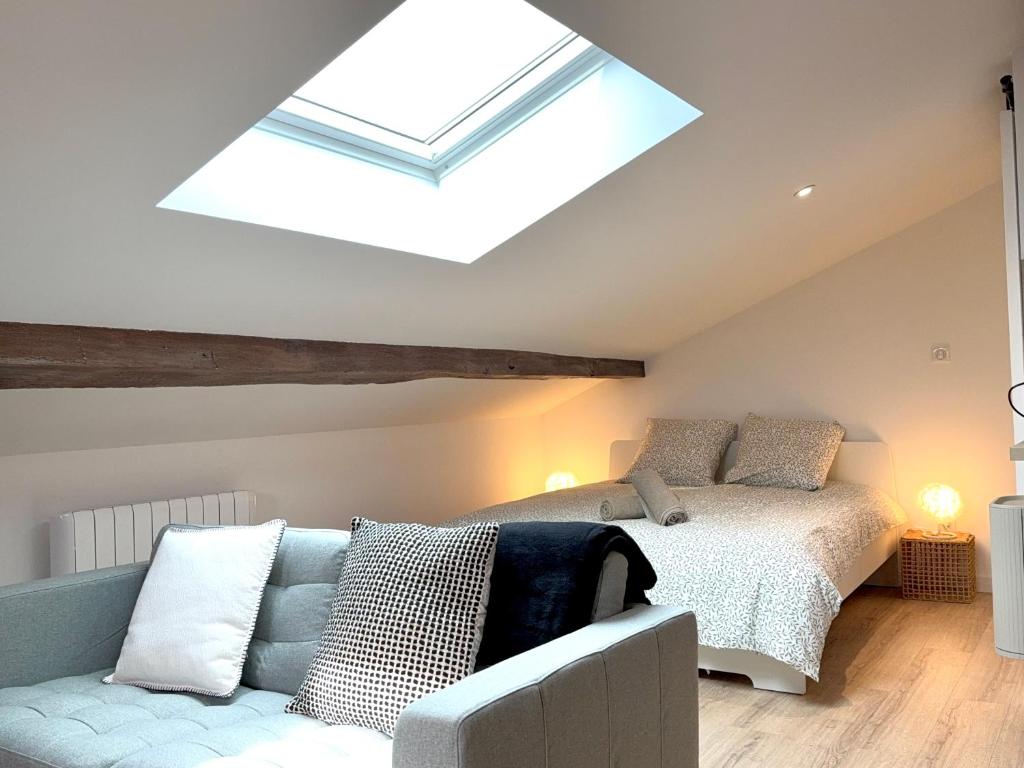 a bedroom with a bed and a couch and a skylight at Rive Gauche Élégante in Belleville-en-Beaujolais