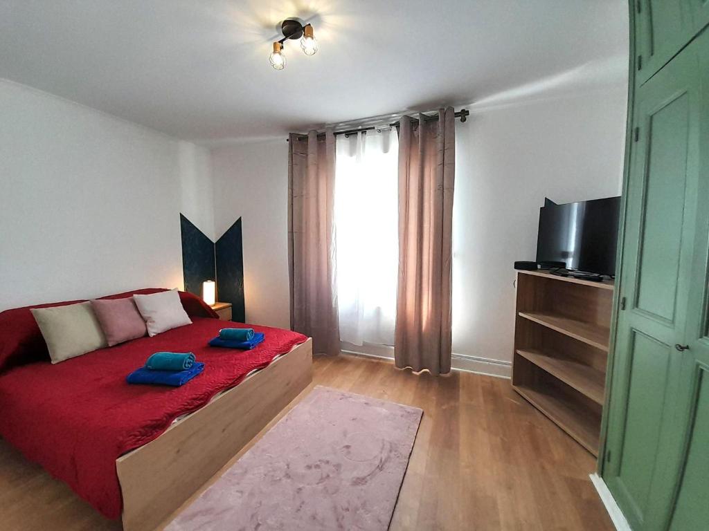 - une chambre avec un lit doté d'une couverture rouge et d'une télévision dans l'établissement appart cosy 2 chb wifi jardin, à Châteauroux