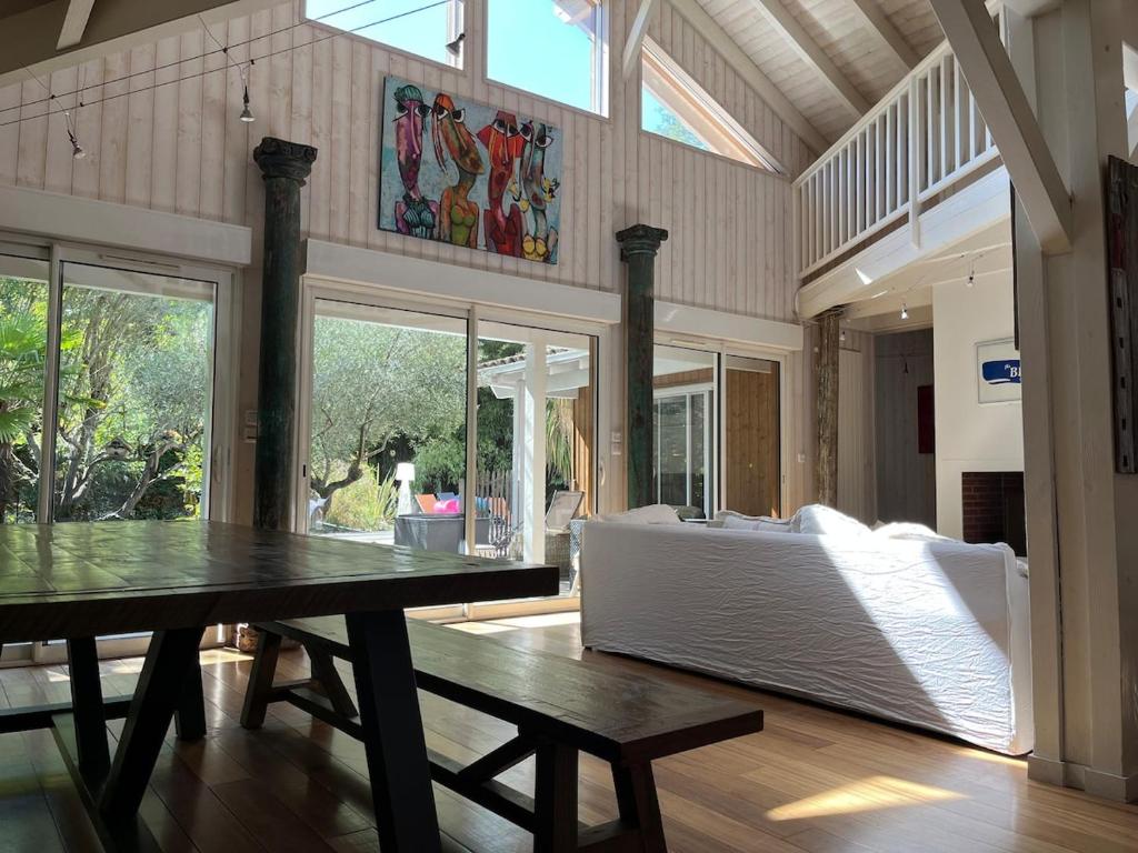 un grand salon avec une table et un canapé dans l'établissement Villa 8 chb au pied de la forêt , 450m du Bassin, à Andernos-les-Bains