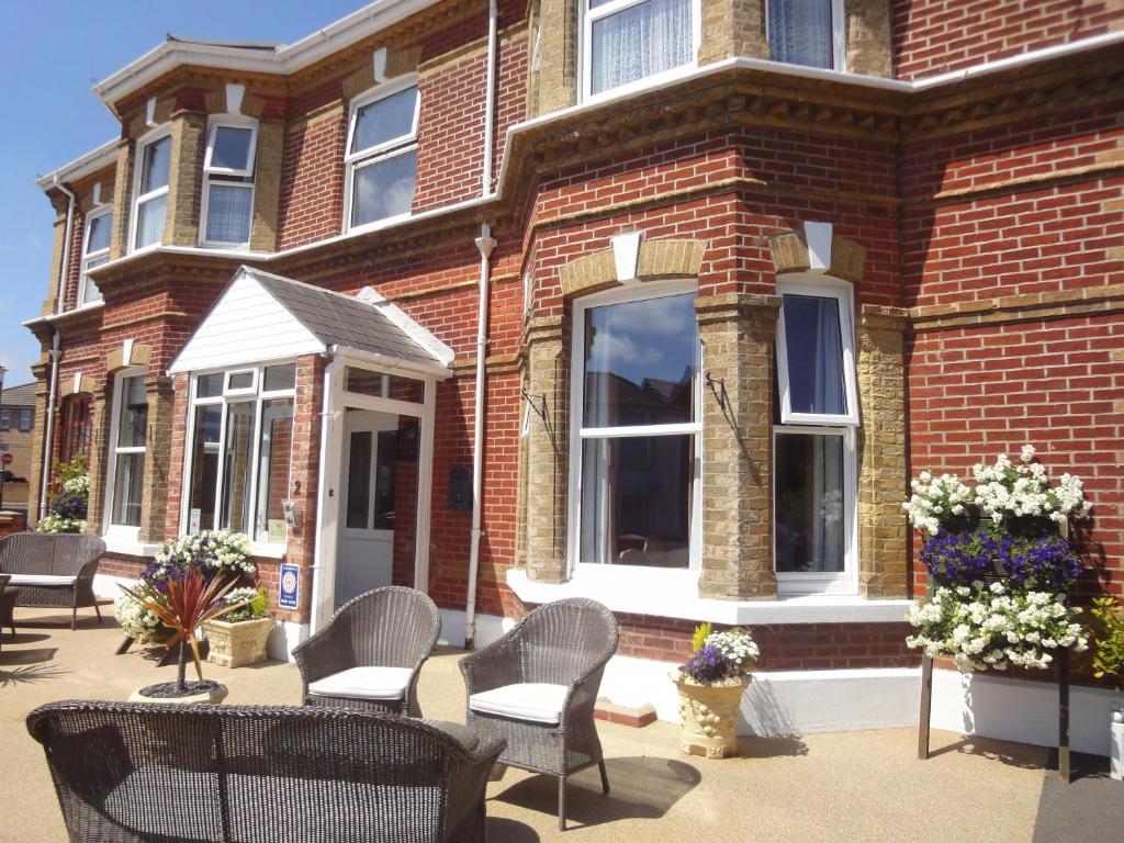 a brick building with chairs and flowers in front of it at Brooke House in Shanklin