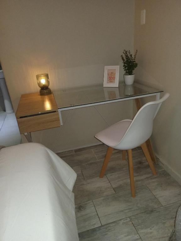 a glass desk with a white chair next to a bed at Simple stay in East London