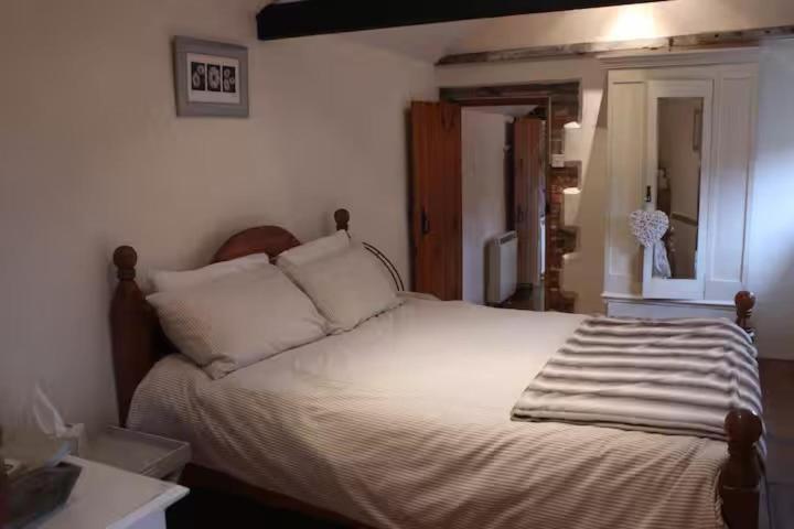 une chambre avec un lit avec des draps blancs et des oreillers dans l'établissement Characterful Cottage Daisy Lodge, à Thornage