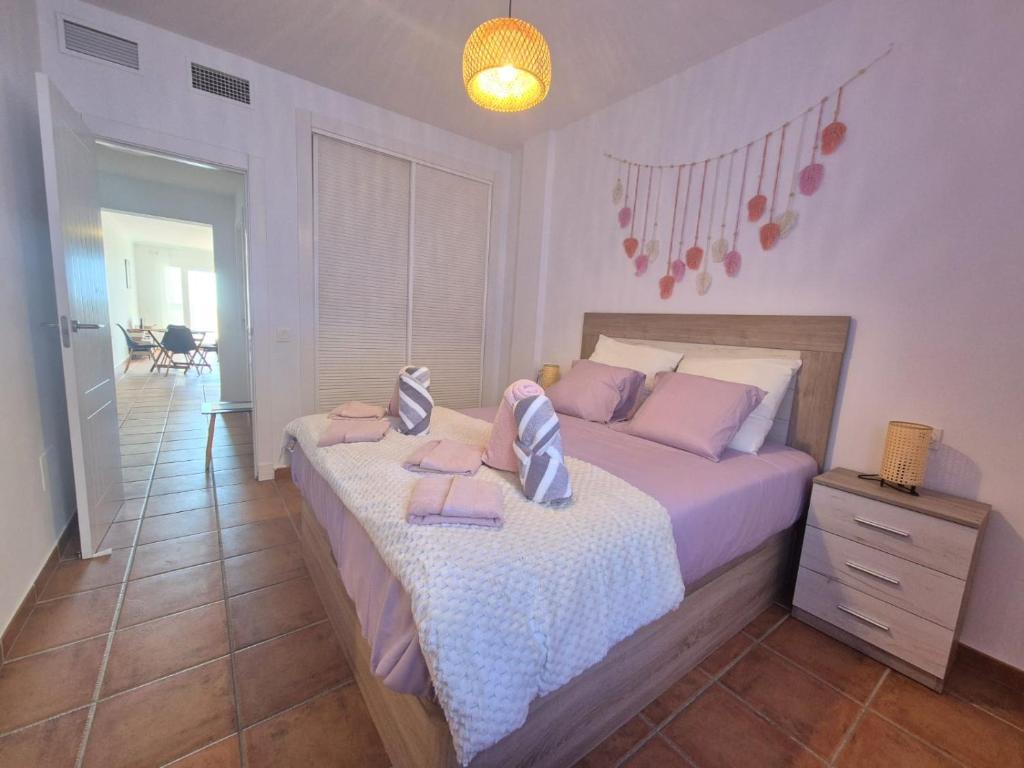 Un dormitorio con una cama con almohadas rosas. en Dihara, en Mojácar