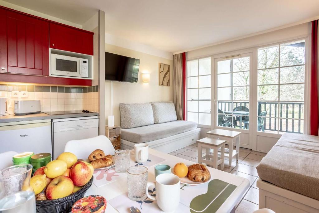 une cuisine avec une table avec un bol de fruits dessus dans l'établissement L'esquiròu, proche du lac, résidence avec piscine, à Biscarrosse