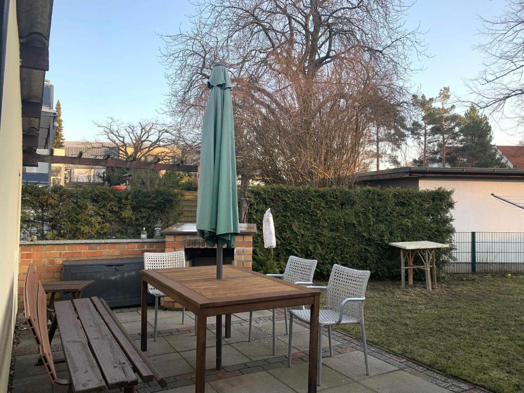 einen Tisch mit einem grünen Sonnenschirm auf einer Terrasse in der Unterkunft Bungalow mit Terrasse in Graal-Müritz