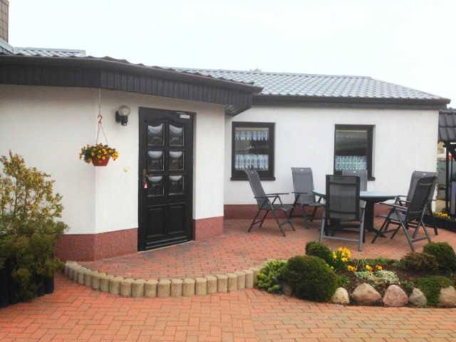 リーブニッツ・ダムガルテンにあるBungalow mit Kamin in Ribnitz-Damgartenの家の前のパティオ(椅子、テーブル付)