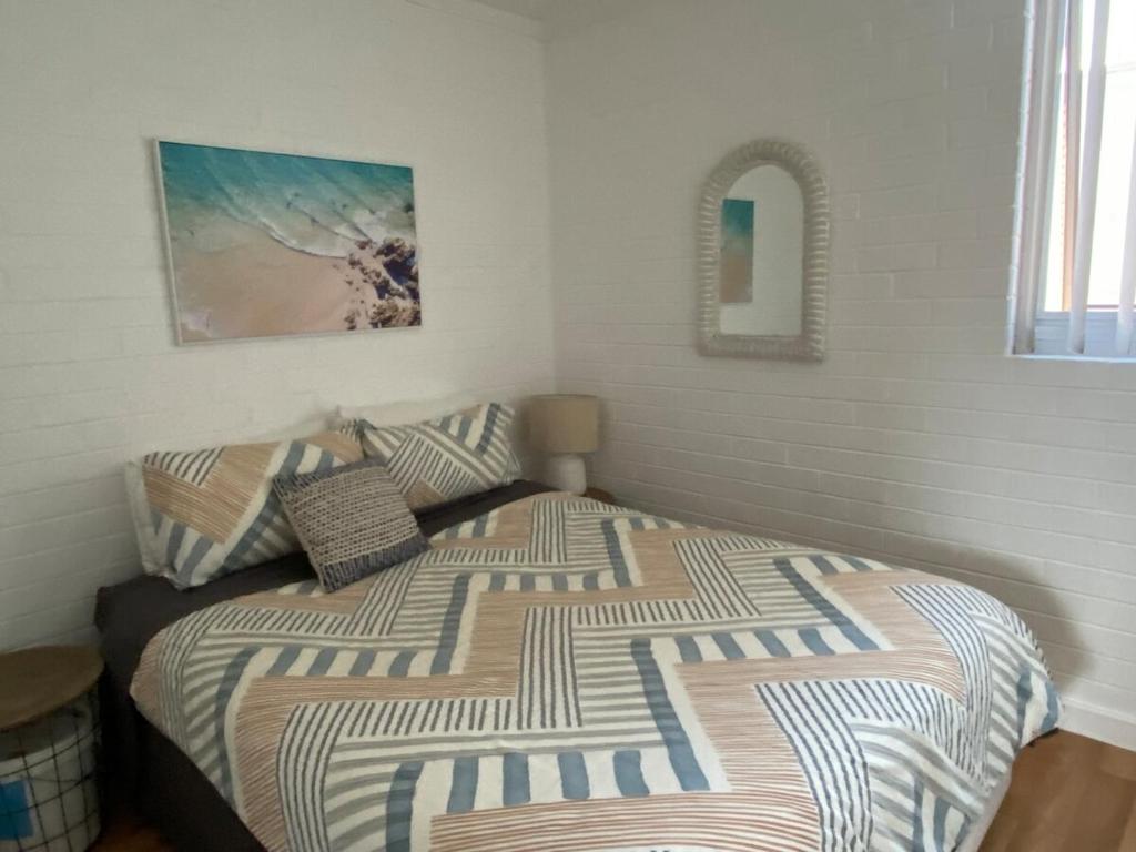 a bedroom with a bed with a comforter and a mirror at CENTRE FREMANTLE 2 queen bedroom APARTMENT in Fremantle