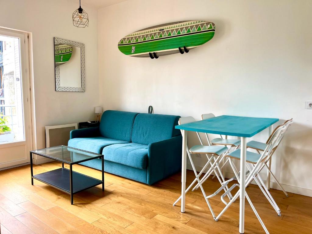 un salon avec un canapé bleu et une table dans l'établissement Deux pièces avec balcon, calme et ensoleillé, à Bordeaux