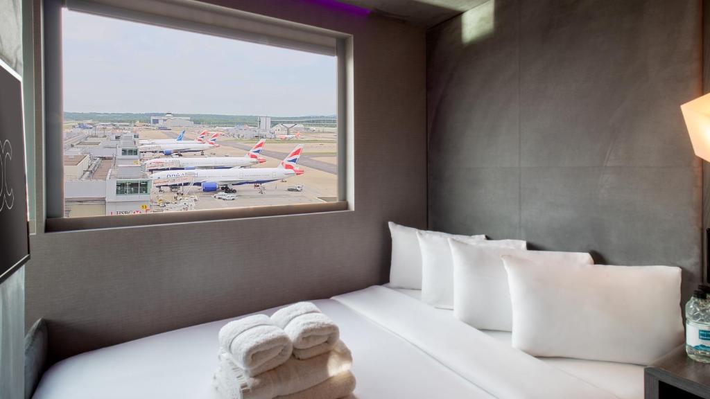 Habitación de hotel con cama con almohadas y ventana en Bloc Hotel London Gatwick Airport, en Horley