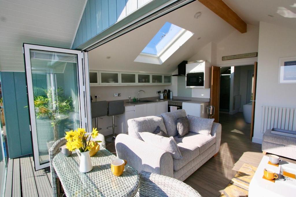 a living room with a couch and a kitchen at Kittiwake Retreat, a luxury escape by the sea! in Gorran Haven
