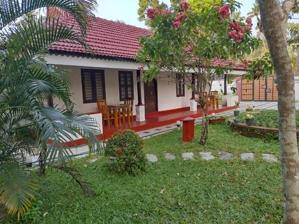 une maison avec un jardin et des chaises en face de celle-ci dans l'établissement Isha Marari Beach homestay, à Mararikulam