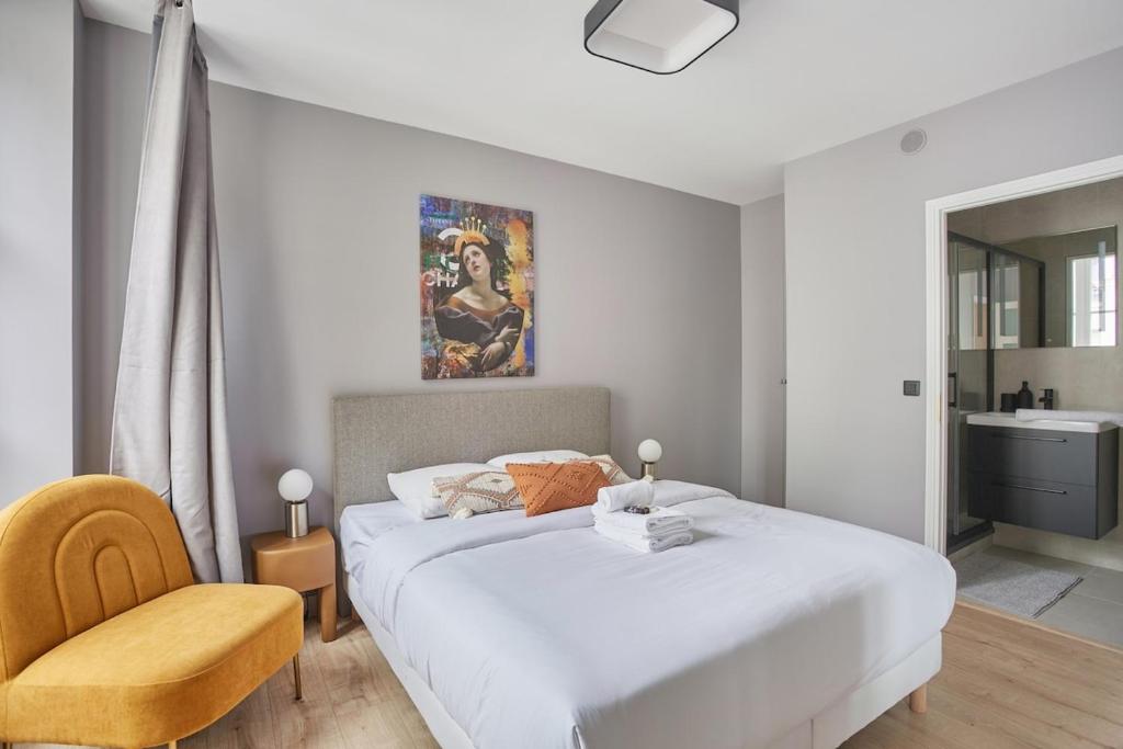 une chambre avec un grand lit blanc et une chaise dans l'établissement Charming apartment 1BR - Montorgueil-Sentier, à Paris