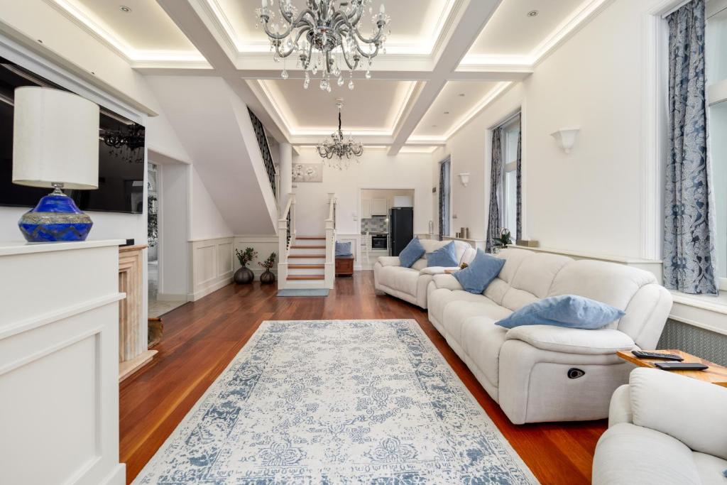 a living room with white furniture and a chandelier at Uhu Villa 750 m2 - Budapest in Budapest