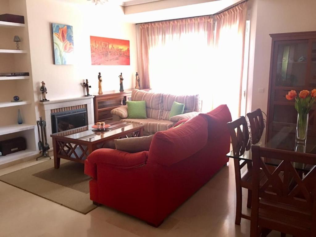 ein Wohnzimmer mit einem roten Sofa und einem Kamin in der Unterkunft Amplio adosado a 5 mits del metro y centro comercial in Mairena del Aljarafe